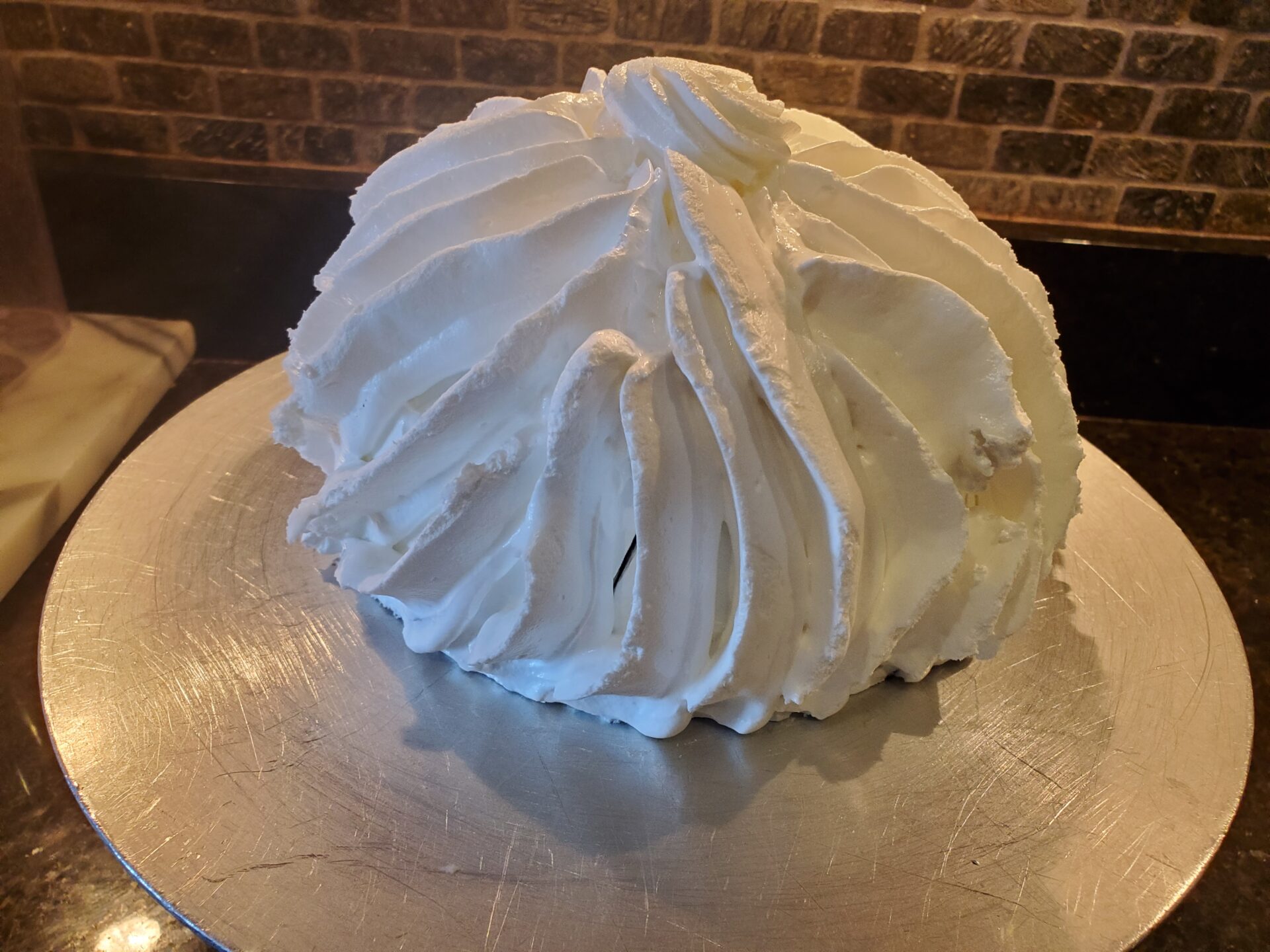 A cake with white frosting on top of a silver plate.