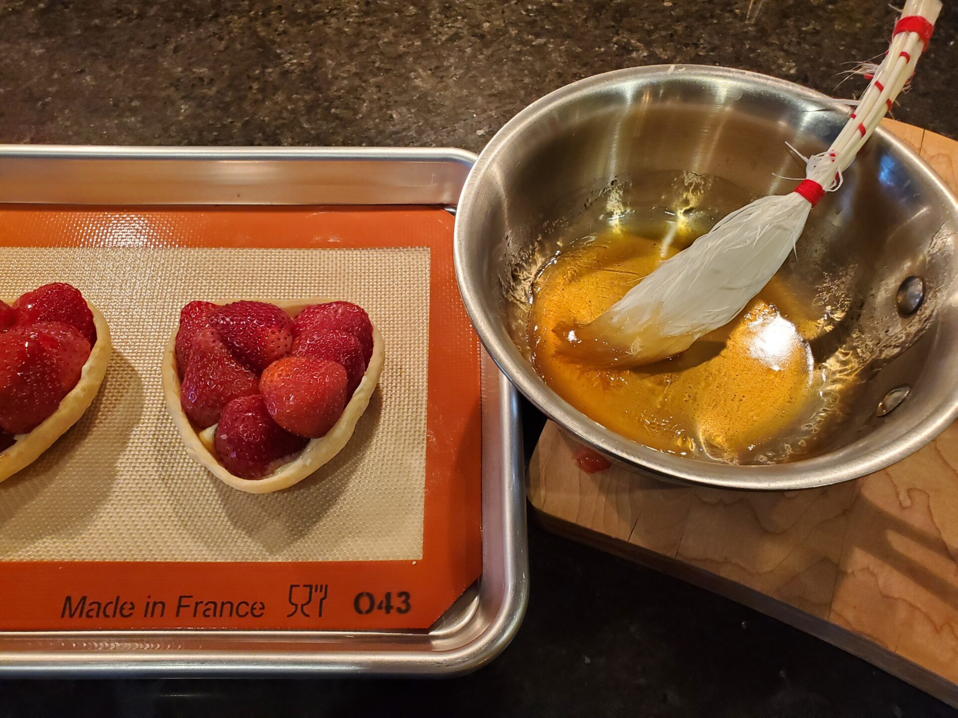 A bowl of fruit and a pan with some strawberries on it