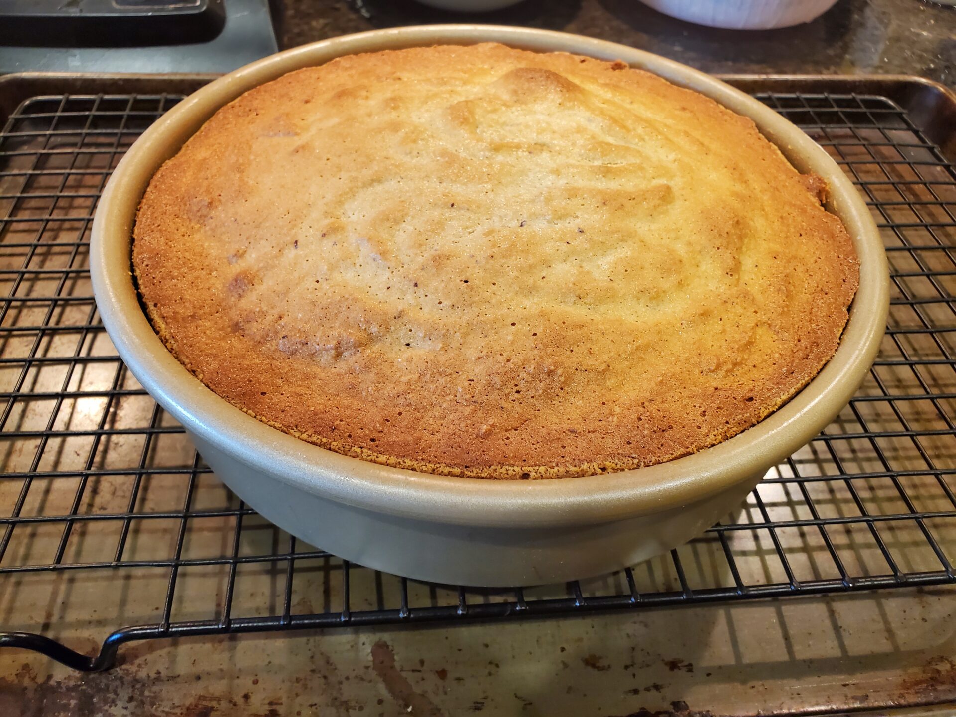 A cake sitting in the middle of a cooling rack.