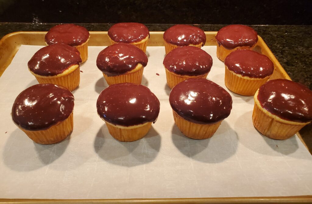 A tray of chocolate covered cupcakes on top of white paper.