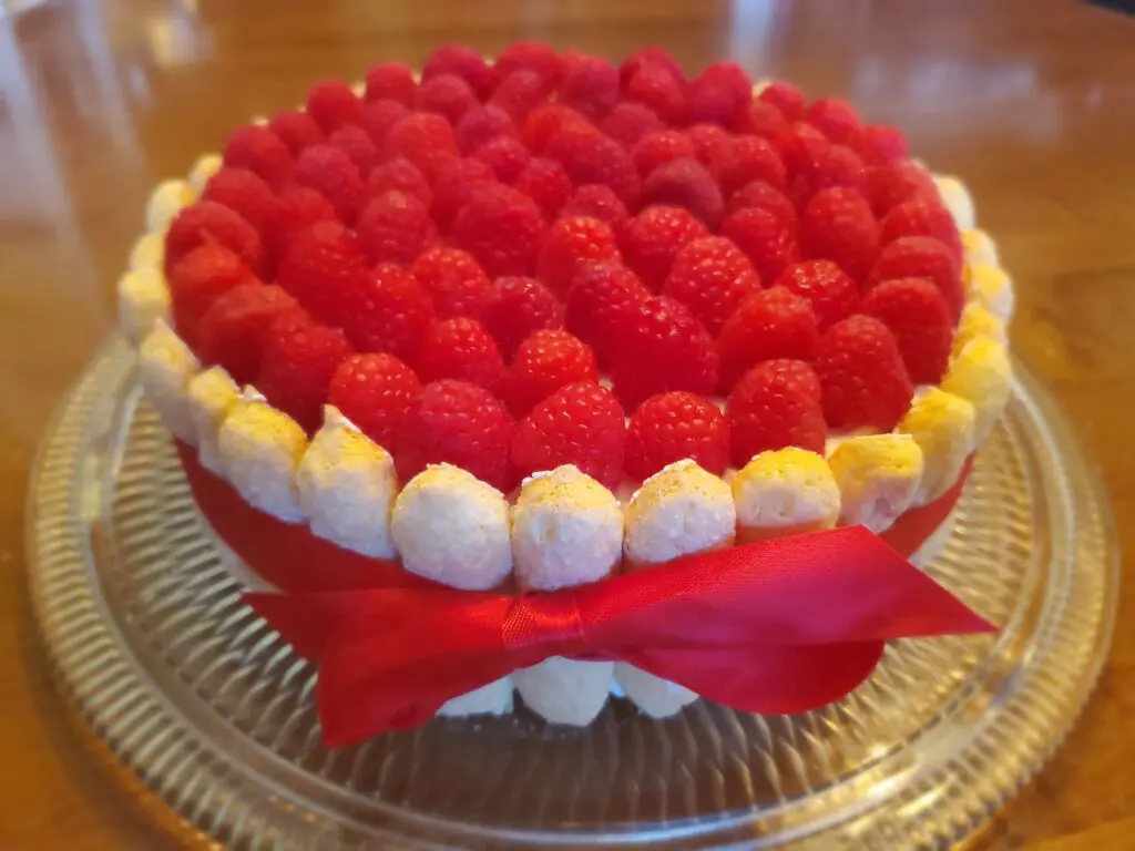 A cake with raspberries on top of it.