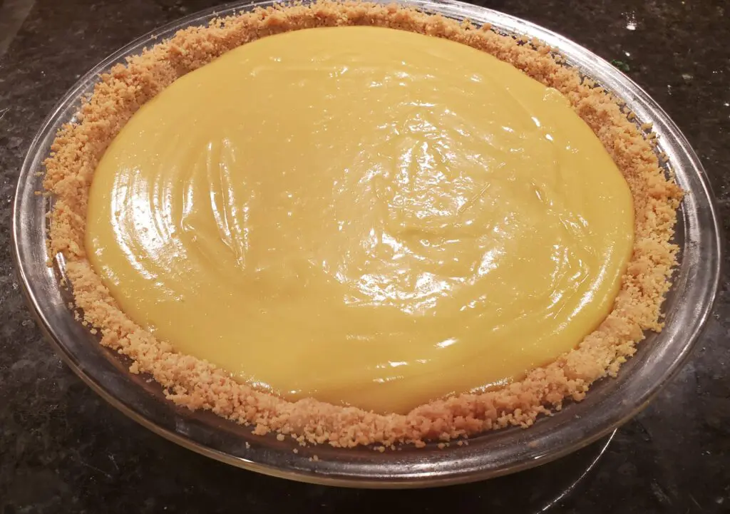 A pie with yellow filling sitting on top of a table.