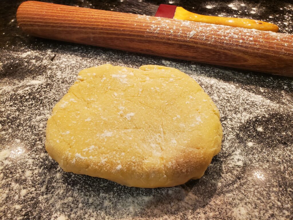 A cookie sitting on top of a table next to a rolling pin.