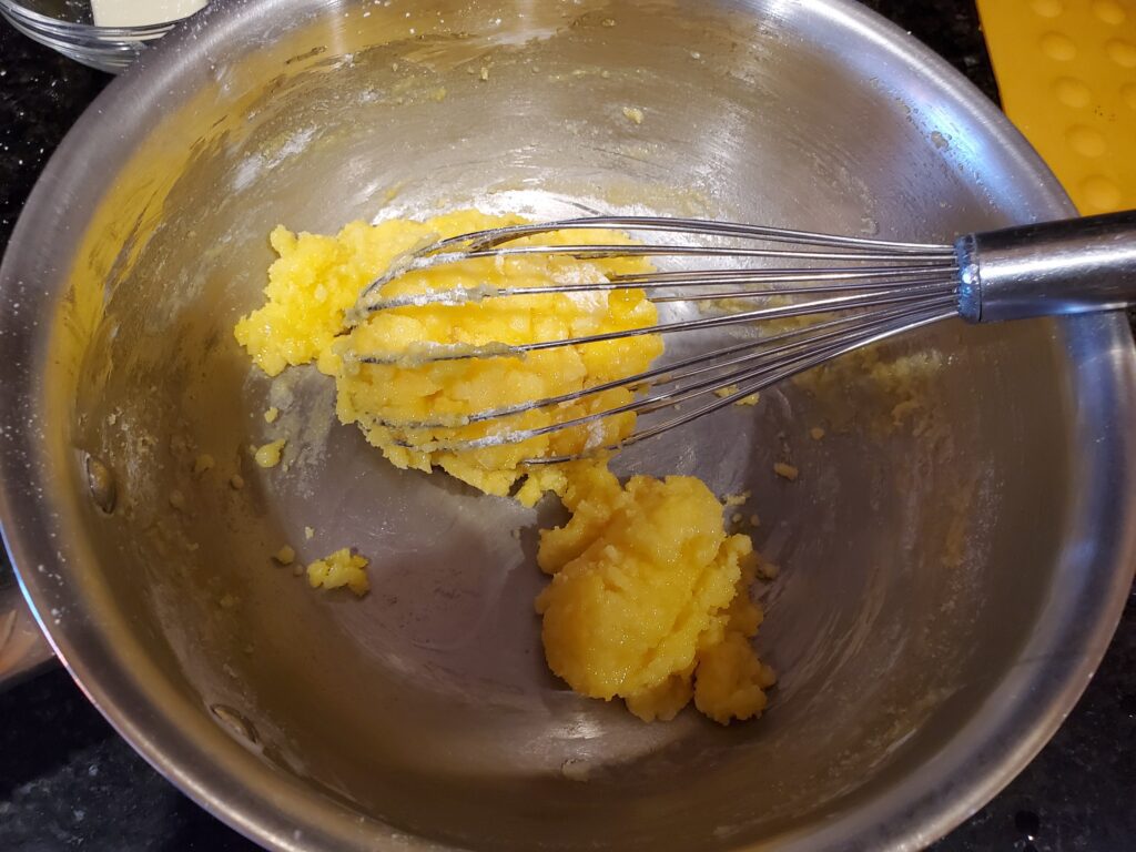 A whisk and some food in a bowl.