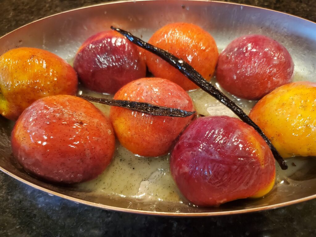 A bowl of apples and vanilla beans in syrup.