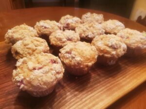 Cranberry muffins on a wooden cutting board.