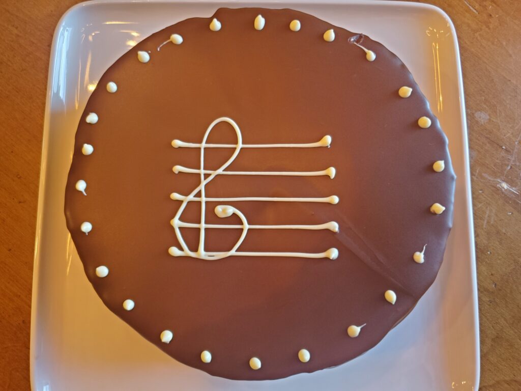 A chocolate cake with white frosting and musical notes.