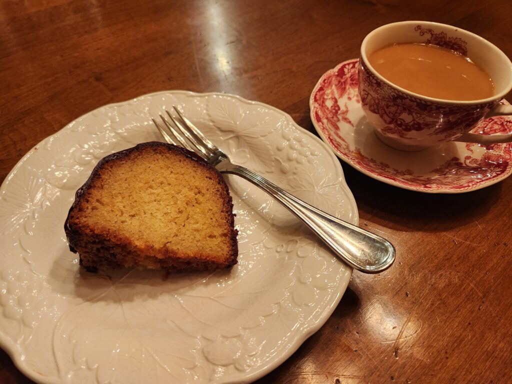 A piece of cake and cup of coffee on a plate.