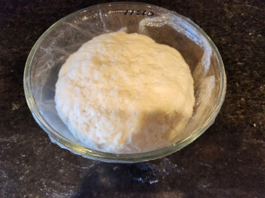 A bowl of dough sitting on top of a table.