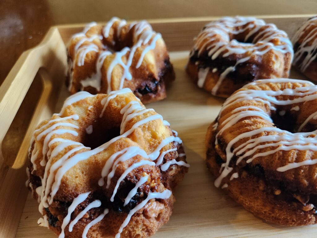 Four donuts on a wooden tray with icing.