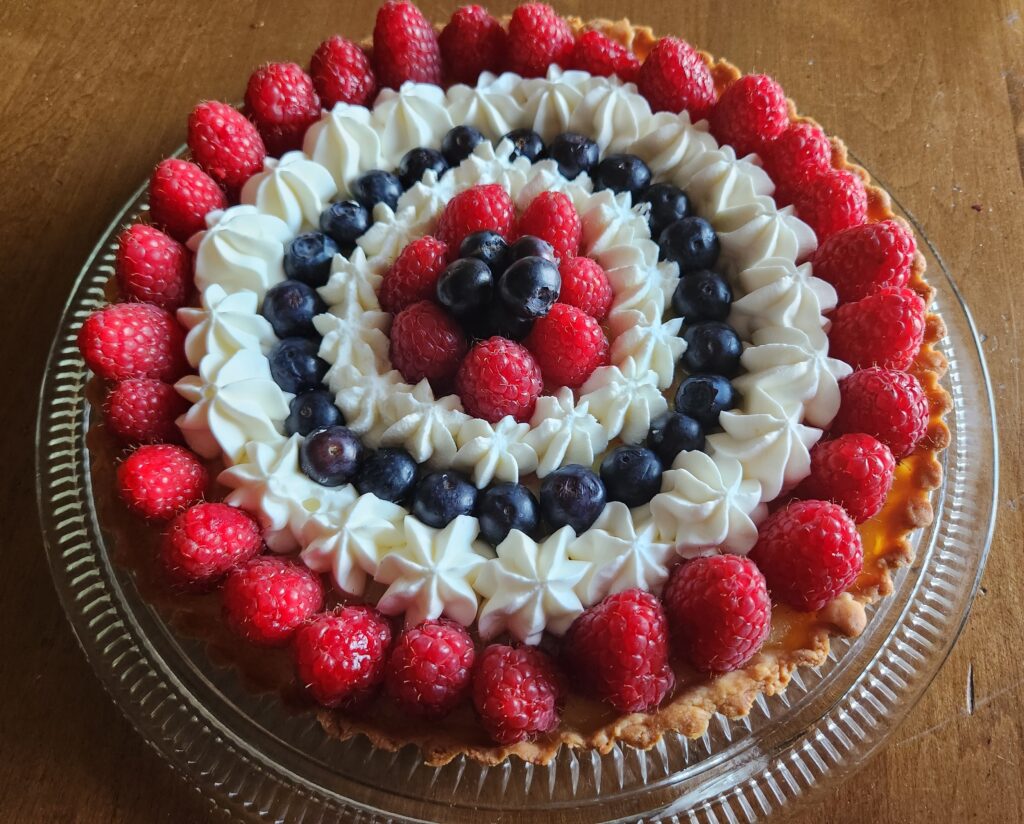 A pie decorated with berries and whipped cream.