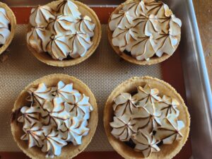 Four meringue pies are sitting on a tray.