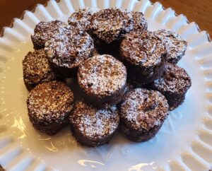 A plate of chocolate brownie bites topped with powdered sugar.