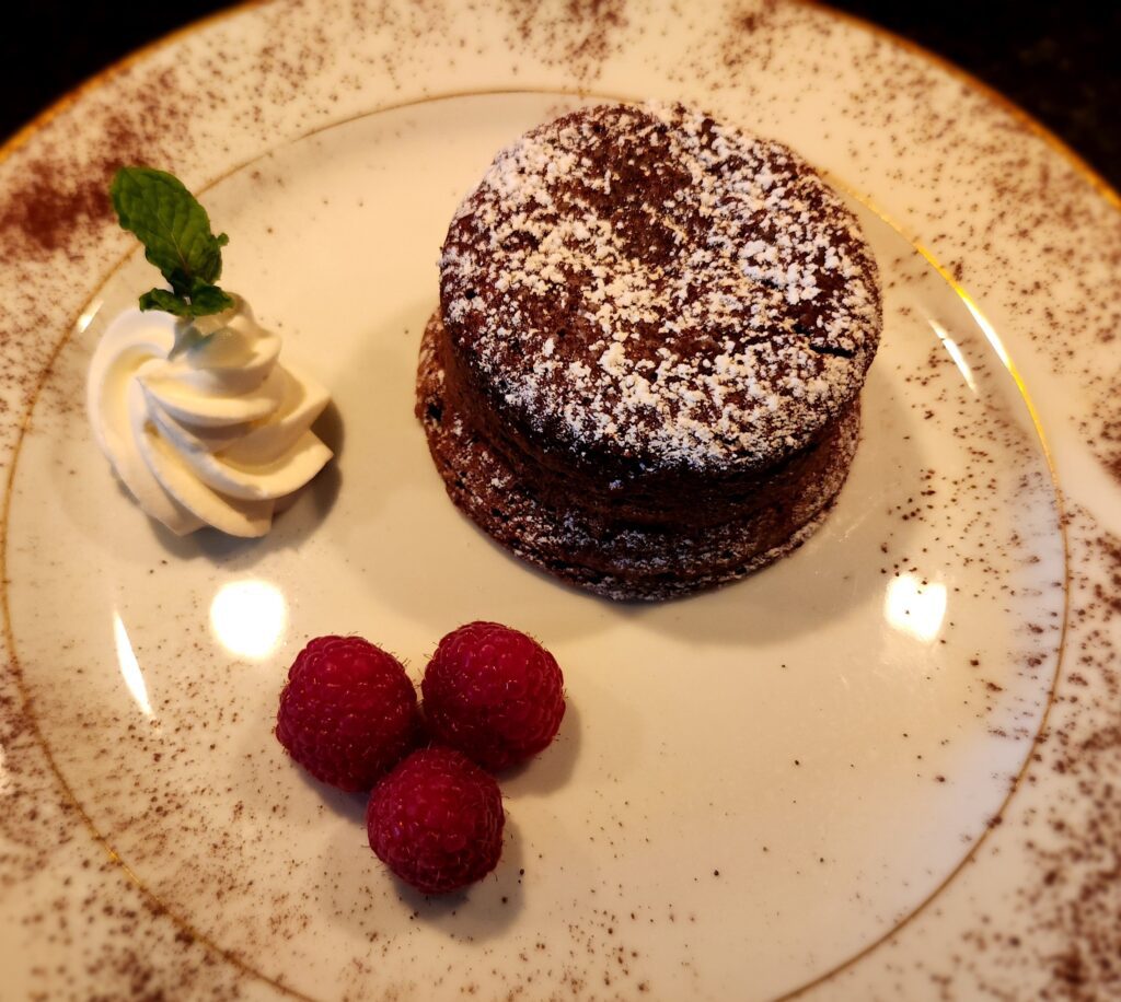 A chocolate cake with raspberries and whipped cream on a plate.