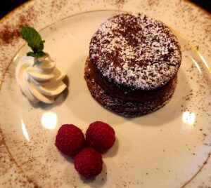 A chocolate cake with raspberries and whipped cream on a plate.