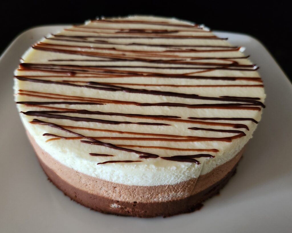 A three tier chocolate cheesecake on a white plate.