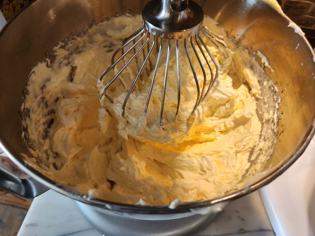 Whipped cream in a mixing bowl with a whisk.