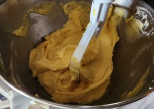 A mixing bowl with a yellow batter in it.