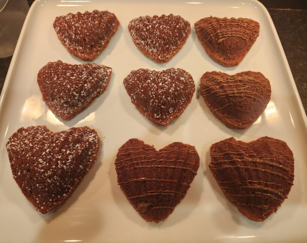 A white plate topped with chocolate hearts covered in sprinkles.