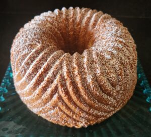 A dusted bundt cake with a fluted design on a green glass plate.