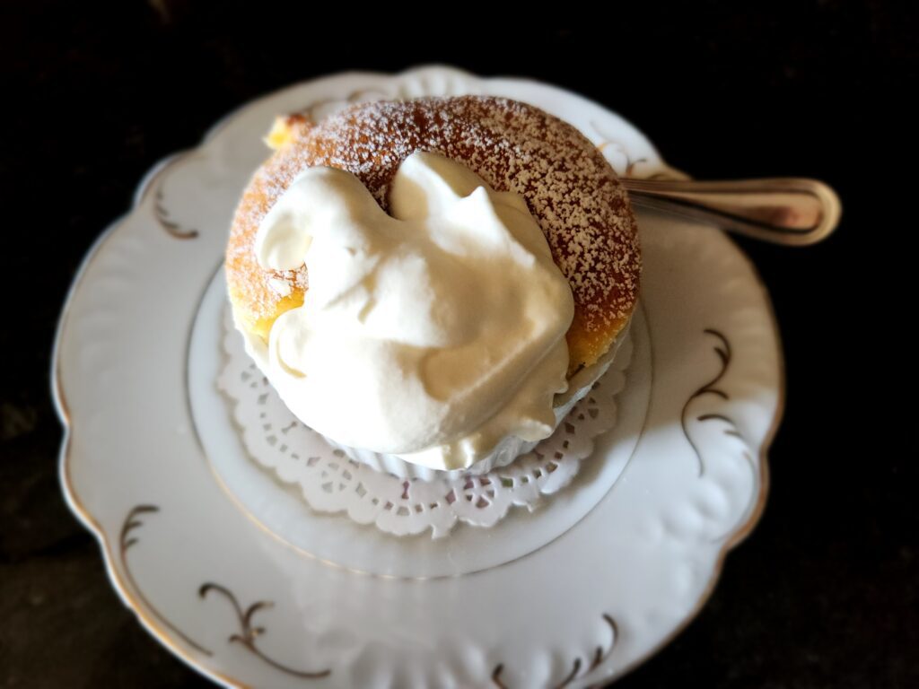 A white plate topped with a cake covered in whipped cream.