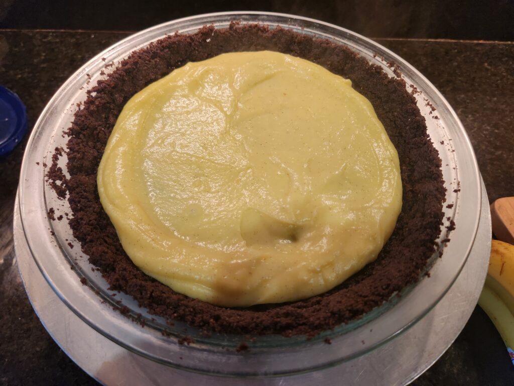 A pie with chocolate crust and yellow frosting.