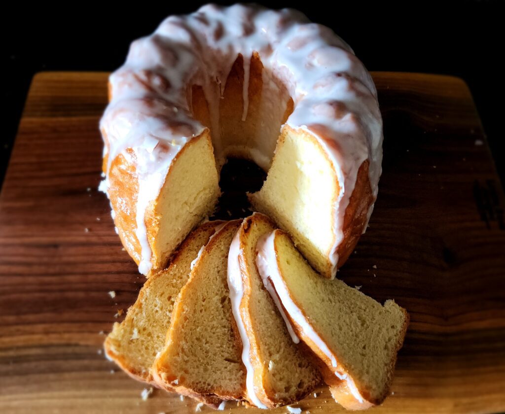 A bundt cake with white frosting on top of a wooden board.