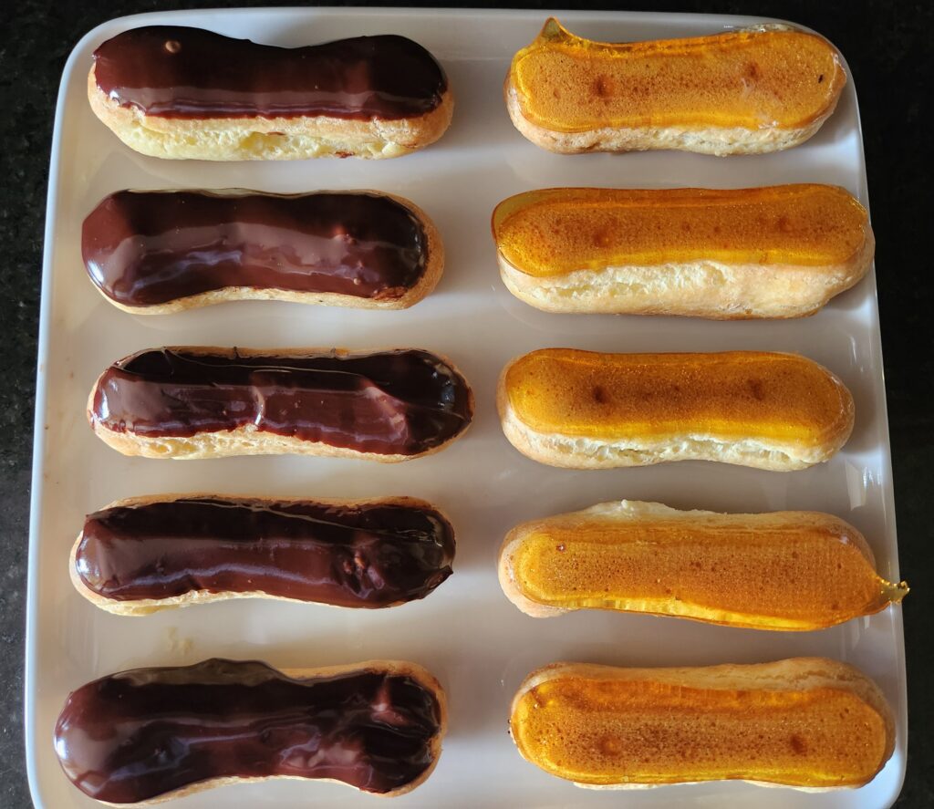 Chocolate and orange eclairs on a plate.