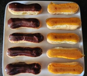 Chocolate and orange eclairs on a plate.