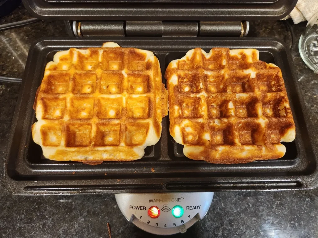 A waffle iron with two waffles in it.