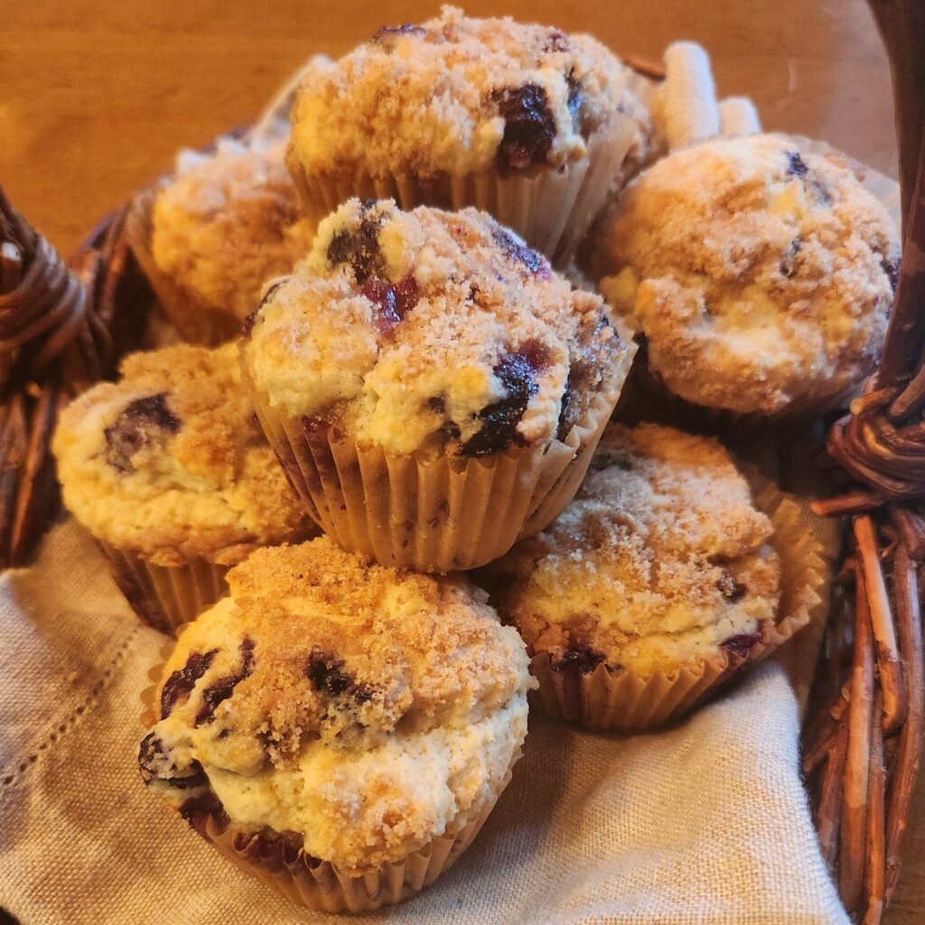 Freshly baked blueberry muffins with crumb topping on a wooden tray.
