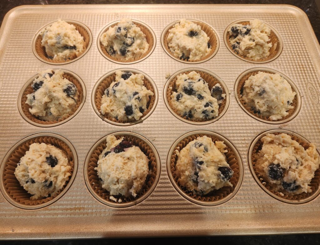 Blueberry muffins batter ready in a muffin tin.