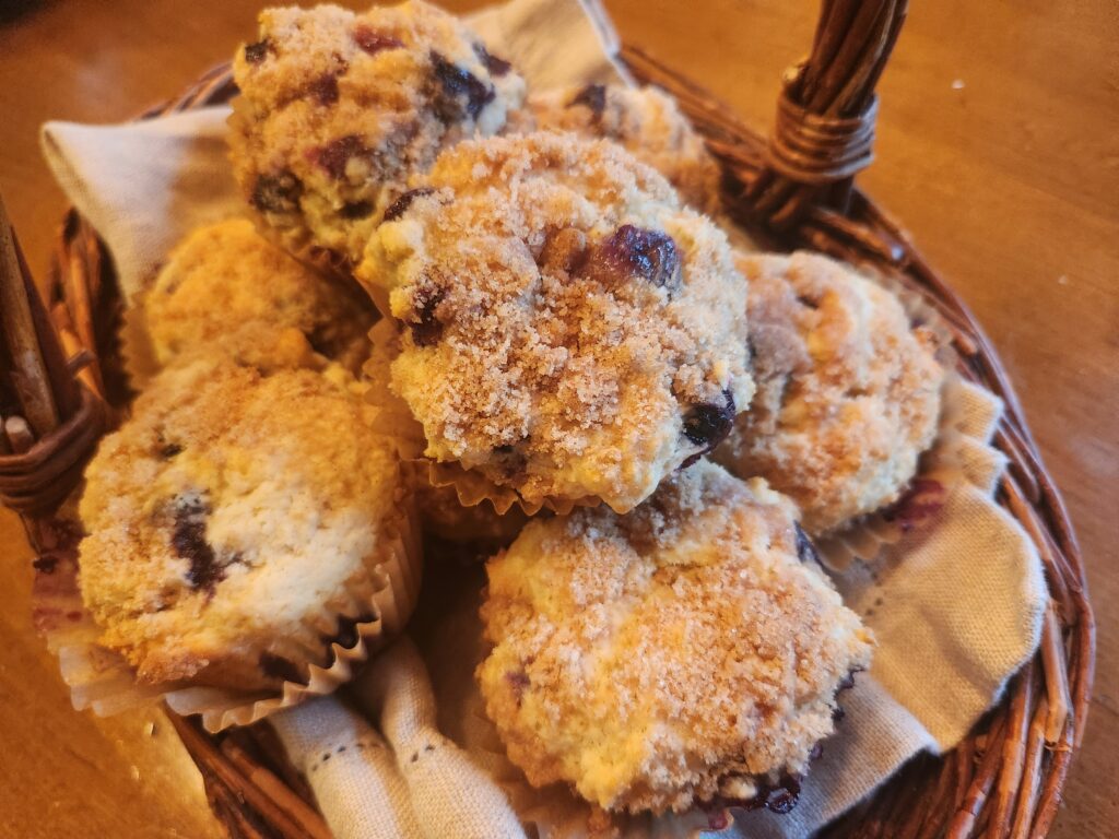 A basket of freshly baked blueberry muffins with a crumbly topping.